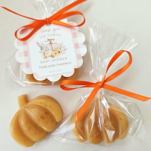 May include: Two small pumpkin-shaped favors wrapped in clear cellophane bags tied with orange ribbon. Each bag has a tag that says "Thank you for coming Baby Shower Marceline Anderson 09.02.2023".