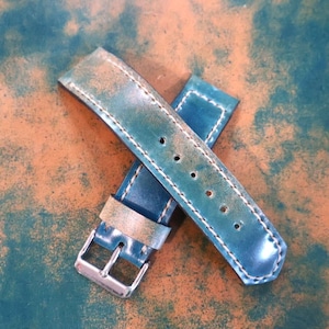 May include: Distressed teal leather watch straps with white stitching. The straps have a silver-colored buckle and multiple adjustment holes. The leather has a worn, vintage appearance.