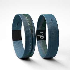 May include: Two blue woven wristbands with a camouflage pattern. One wristband has the text "Find your calm" and the other has the initials "MB".