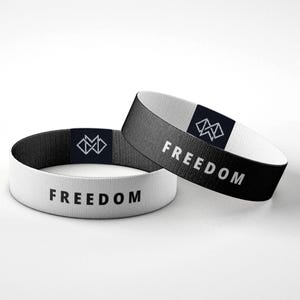 Puede incluir: Dos pulseras el&aacute;sticas, una blanca y otra negra, con la palabra &laquo;FREEDOM&raquo; impresa en blanco. Cada pulsera presenta un peque&ntilde;o logotipo geom&eacute;trico en una etiqueta azul marino.