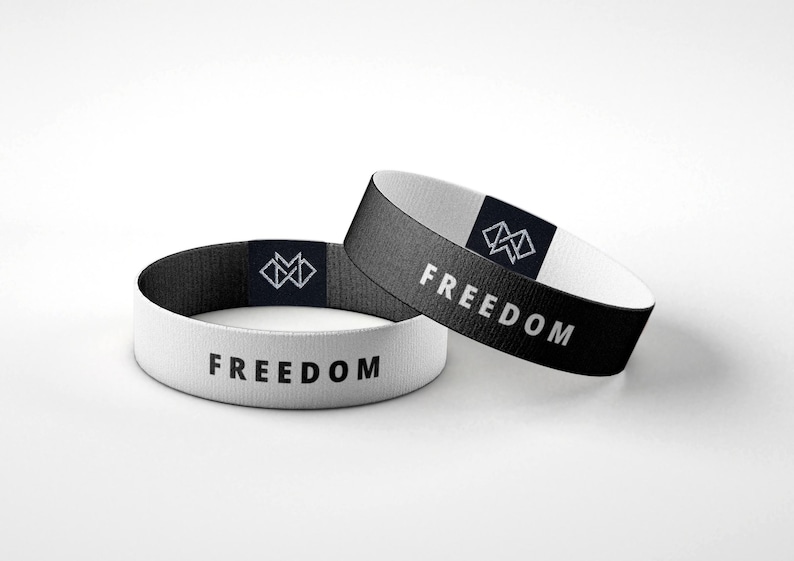 Puede incluir: Dos pulseras el&aacute;sticas, una blanca y otra negra, con la palabra &laquo;FREEDOM&raquo; impresa en blanco. Cada pulsera presenta un peque&ntilde;o logotipo geom&eacute;trico en una etiqueta azul marino.