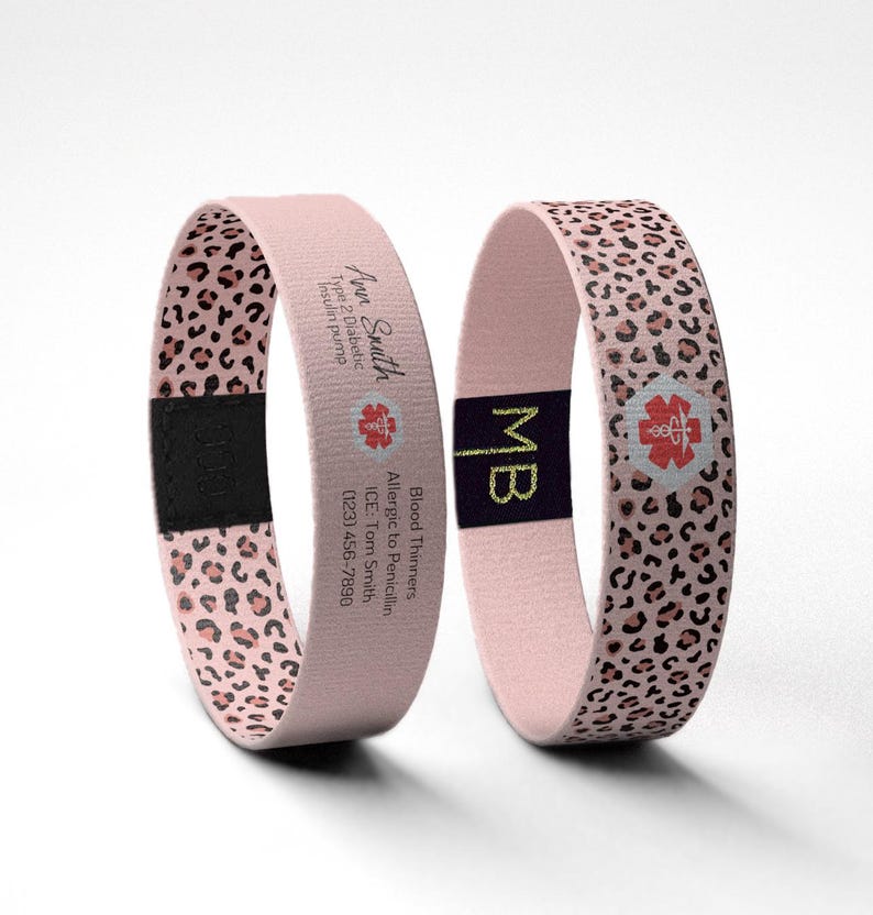 May include: Two pink medical alert bracelets. One bracelet has a leopard print pattern and the other has the text "Ann Smith, Type 2 Diabetic, Insulin pump" and a medical symbol. The second bracelet has the initials "MB" and a medical symbol.