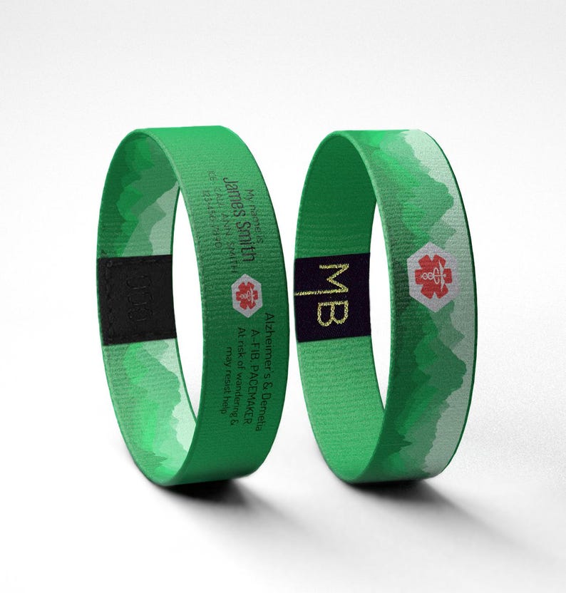 May include: Two green medical alert bracelets. One bracelet has the name "James Smith", a medical symbol, and contact information. The other bracelet has the initials "MB" and a medical symbol. Both bracelets have a mountain design.