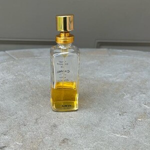 Puede incluir: Un frasco de perfume transparente y rectangular con tap&oacute;n y detalles dorados. El frasco contiene un l&iacute;quido amarillo y tiene el nombre de la marca "CHANEL" impreso. El frasco es un envase de perfume cl&aacute;sico.