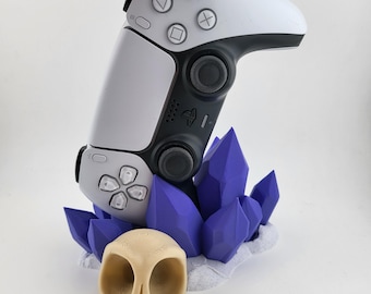 Suporte para controle de ps5 com cristais roxos em uma base branca e um suporte para joystick em forma de caveira marrom claro