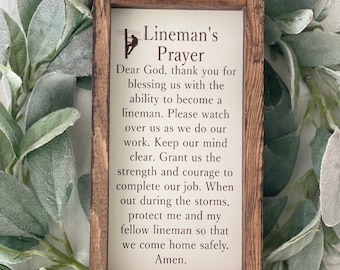 May include: A wooden sign with a white background and brown frame. The sign has a silhouette of a lineman climbing a pole and the text "Lineman's Prayer". The text reads: "Dear God, thank you for blessing us with the ability to become a lineman. Please watch over us as we do our work. Keep our mind clear. Grant us the strength and courage to complete our job. When out during the storms, protect me and my fellow lineman so that we come home safely. Amen."