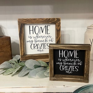 May include: Two wooden signs with the text "HOME is wherever my bunch of CRAZIES are" on them. The signs are in different sizes and have a rustic brown finish.