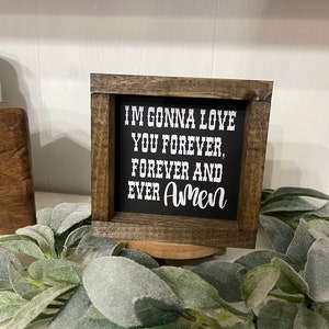 May include: A small wooden sign with a black background and white text that reads "I'm gonna love you forever, forever and ever Amen".