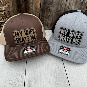 May include: Two trucker hats with the text "MY WIFE BEATS ME" on a rectangular patch. One hat is brown with a tan mesh back, and the other is gray with a black mesh back. Both hats have a Richardson 112 tag.