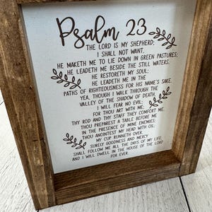 Puede incluir: Un letrero de madera enmarcado con el texto del Salmo 23 impreso sobre un fondo blanco. El texto est&aacute; en una fuente de escritura marr&oacute;n oscuro, y el marco es de color marr&oacute;n oscuro. El letrero es un art&iacute;culo decorativo.