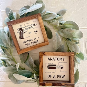 May include: Two wooden signs with a white background and brown text. The top sign features a cartoon illustration of a handgun with the text "Anatomy of a Pew Pewer". The bottom sign features a cartoon illustration of a bullet with the text "Anatomy of a Pew".