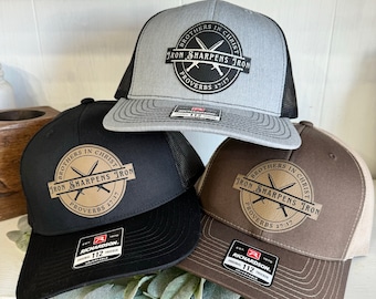May include: Three brown, black, and gray trucker hats with a brown leather patch that says "Brothers in Christ, Iron Sharpens Iron, Proverbs 27:17".