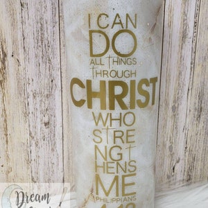 May include: A white tumbler with a gold glitter finish and gold lettering that reads "I can do all things through Christ who strengthens me Philippians 4:13".