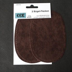 Könnte beinhalten: Zwei braune Wildleder-Bügeleisen-Flicken zum Reparieren oder Dekorieren von Kleidung. Die Flicken sind oval geformt und haben einen genähten Rand. Die Verpackung lautet "2 Bügel-Flecken aus Wildlederimitat ... einfach aufbügeln-fertig".