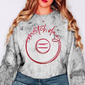May include: A gray and white acid-wash sweatshirt featuring the red text "match day" written in a cursive script above a red circular graphic with two horizontal lines inside. The long-sleeve pullover has a crew neckline and a relaxed fit.