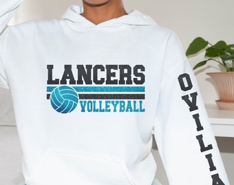 Może przedstawiać: Biała bluza z kapturem z napisem "LANCERS" czarnymi literami blokowymi nad niebiesko-czarnym paskiem i grafiką do siatkówki. Słowo "VOLLEYBALL" znajduje się pod grafiką w kolorze niebieskim. Prawy rękaw ma czarny napis "OVILIA".