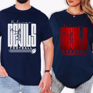 May include: Two navy blue t-shirts with the text "Bolivar Devils". One shirt has white text and a football graphic, the other has red text and a soccer ball graphic. The shirts are short-sleeved.