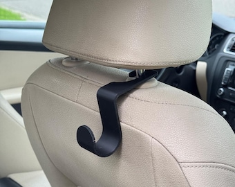 May include: Black plastic hook designed to hang items from the headrest of a car seat.