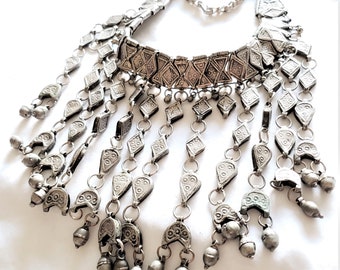 May include: A silver necklace with a geometric design and multiple dangling charms. The necklace is made of metal and has a silver finish.
