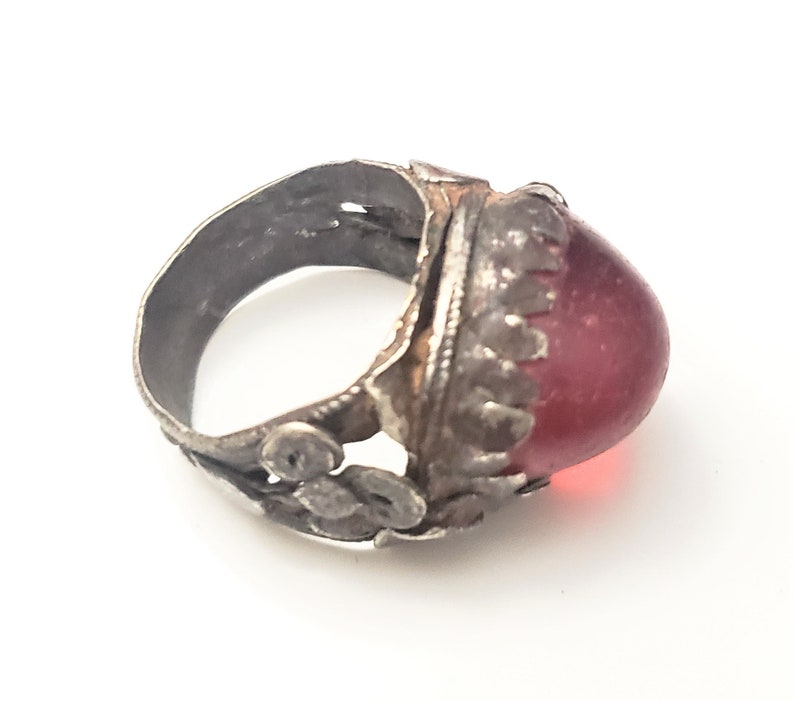 Puede incluir: Un anillo de plata con un dise&ntilde;o adornado y una gran piedra roja de forma ovalada.