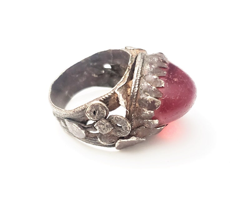 Puede incluir: Un anillo de plata con un dise&ntilde;o adornado y una piedra grande de vidrio rojo.