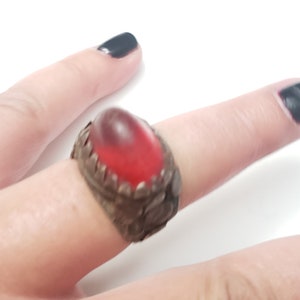 Puede incluir: Un anillo de plata con un dise&ntilde;o adornado y una piedra de vidrio roja.
