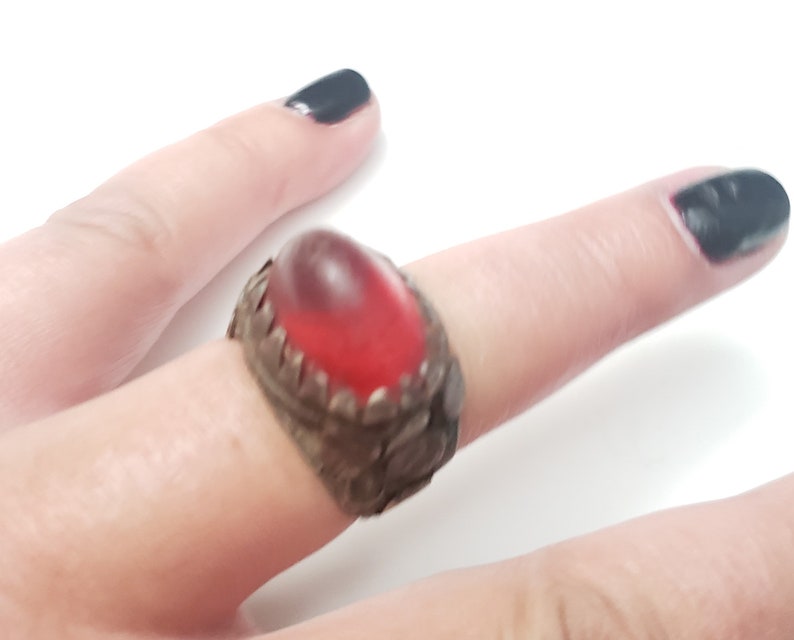 Puede incluir: Un anillo de plata con un dise&ntilde;o adornado y una piedra de vidrio roja.