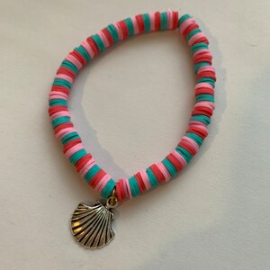 May include: A pink and teal beaded bracelet with a silver seashell charm.