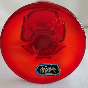 May include: The bottom of a red glass goblet with a Noritake Perspective Japan label.