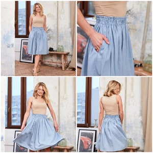 May include: A light blue skirt with a gathered elastic waistband. The skirt is made of a soft, lightweight fabric and falls to the knee. The model is wearing a beige tank top with the skirt.