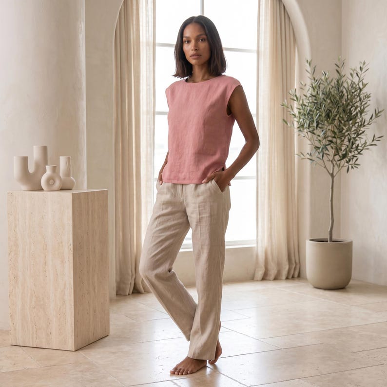 May include: A sleeveless dusty rose top with a round neckline and straight-leg beige trousers. The top features a simple cut with wide shoulders, while the trousers have a clean, tailored fit with side pockets and a visible front seam detail.