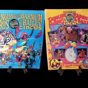 May include: Two vintage Ringling Bros. and Barnum & Bailey Circus posters. The left poster features a tiger and a man in a blue and yellow costume. The right poster features a man in a red shirt holding a leopard and a unicorn. The text on the posters reads "Ringling Bros. and Barnum & Bailey Circus" and "The Greatest Show on Earth".