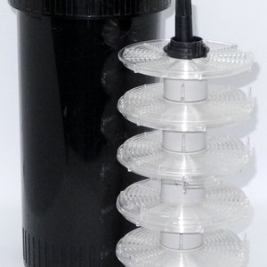 Może przedstawiać: Czarny plastikowy zbiornik do wywoływania filmu z szarym wieczkiem i przezroczystą plastikową szpulą do filmu z pięcioma szpulami.