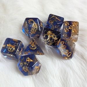 May include: A set of eight blue and gold dice with glitter and gold accents. The dice are numbered 1-6, 1-20, 1-10, 1-8, 1-4, and 1-12.