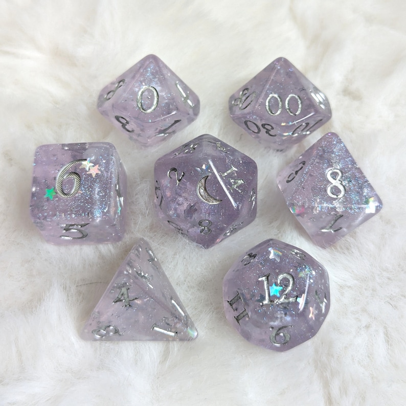 May include: Set of seven iridescent purple dice with silver glitter and numbers. The dice are a d4, d6, d8, d10, d%, d12, and d20.