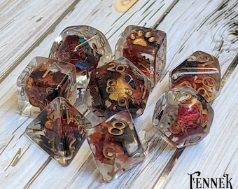 May include: Set of eight clear resin dice with gold accents and dried flowers and leaves embedded inside. The dice are numbered 1-6 and have a paw print on one side.