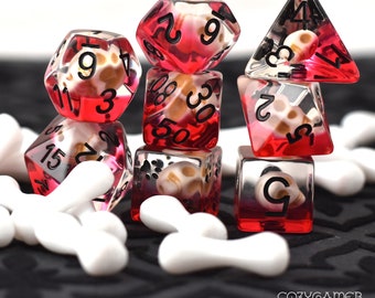 May include: A set of six red and clear dice with white skull and bone designs. The dice are stacked on top of each other and surrounded by white bone-shaped objects.