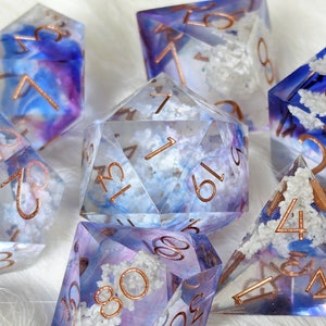 May include: Set of eight polyhedral dice with a cloudy, blue and purple swirl design. The dice are made of clear resin with white glitter and have copper-colored numbers.