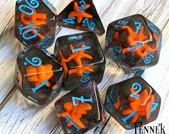 May include: Set of seven black and orange dice with blue numbers and a starfish design. The dice are translucent and have a glittery finish.