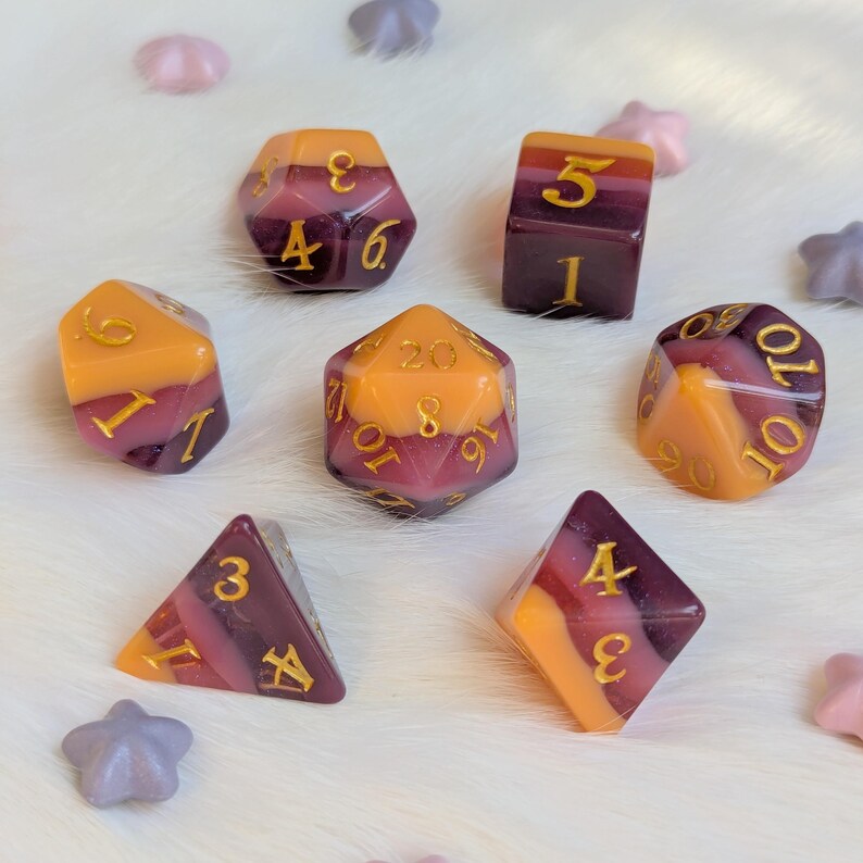 May include: Set of eight polyhedral dice with a swirl of pink, purple, and yellow. The dice are numbered 1-20.