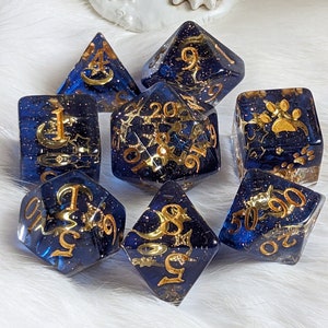 May include: Set of seven blue and gold dice with glitter and gold accents. The dice are numbered 1 through 20.