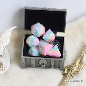 May include: A set of six pastel-colored dice with white numbers in a silver treasure chest. The dice are a mix of pink, blue, and green.