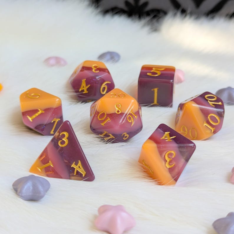 May include: Set of eight polyhedral dice with a swirl of orange and purple. The dice are numbered 1 through 10.