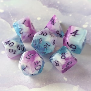 Puede incluir: Un conjunto de seis dados iridiscentes con un patrón de remolino de púrpura y azul. Los dados están numerados del 1 al 20.