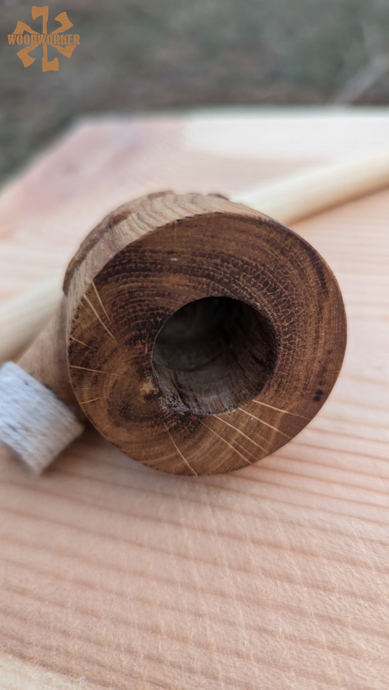 Pu&ograve; includere: Primo piano di una pipa di legno con una finitura marrone naturale. La pipa &egrave; realizzata in un unico pezzo di legno e ha una superficie liscia e lucida. La ciotola della pipa &egrave; rotonda e ha un piccolo foro al centro. Il gambo della pipa &egrave; dritto ed &egrave; attaccato alla ciotola. La pipa &egrave; appoggiata su una superficie di legno.
