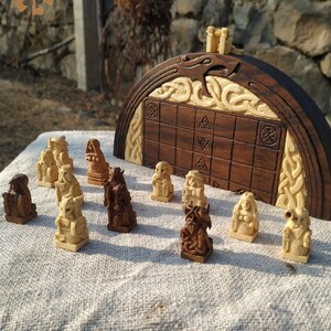 Puede incluir: Un juego de ajedrez de madera hecho a mano con piezas talladas intrincadamente y un tablero decorativo. Las piezas son en tonos de madera claros y oscuros, dispuestas en un tablero a cuadros. El juego presenta un dise&ntilde;o art&iacute;stico &uacute;nico.