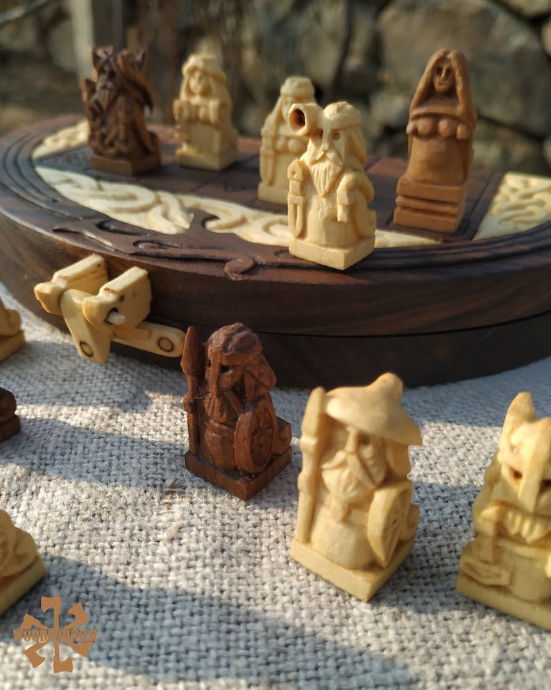 Puede incluir: Juego de mesa de madera con piezas talladas. Las piezas, en tonos marrones y beige, representan figuras con detalles. El tablero, marr&oacute;n oscuro, tiene incrustaciones claras, creando un contraste visual.