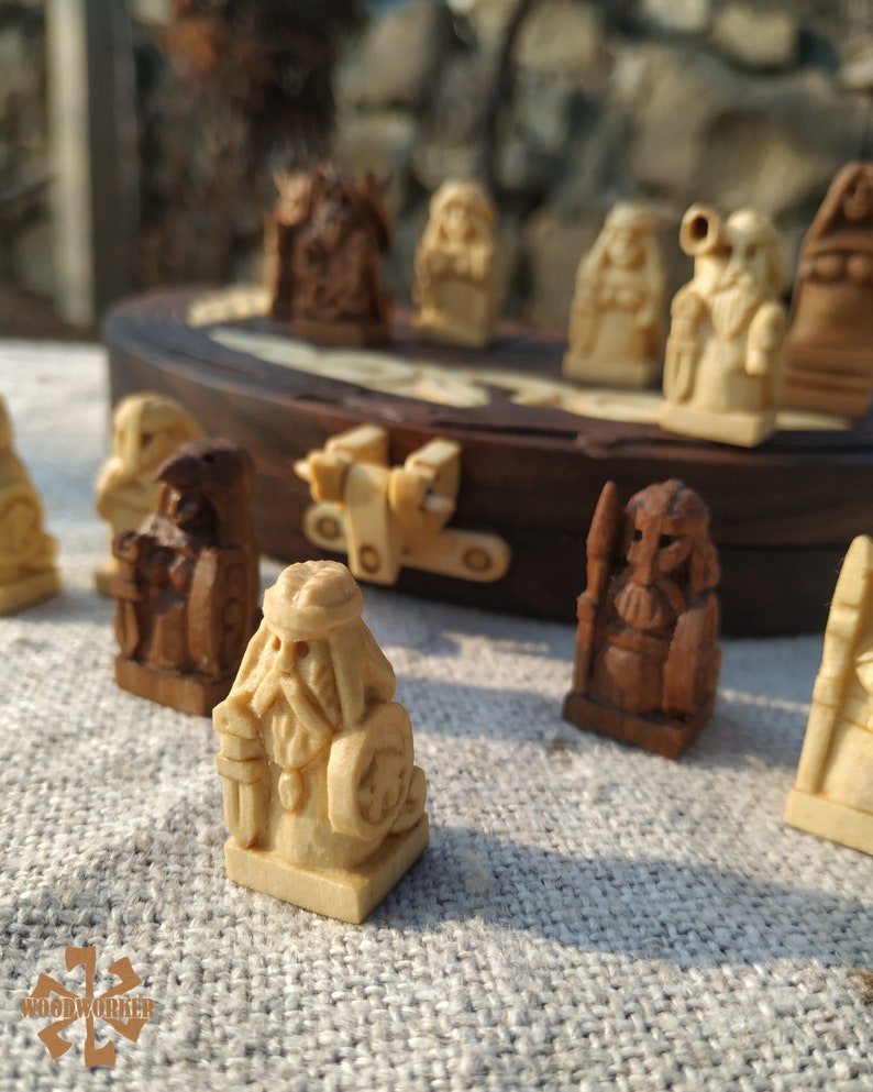 Puede incluir: Un juego de ajedrez de madera con piezas talladas intrincadamente. Las piezas son en tonos marr&oacute;n claro y oscuro, que representan figuras con detalles. El tablero de ajedrez es visible en el fondo, con un marco de madera oscura.