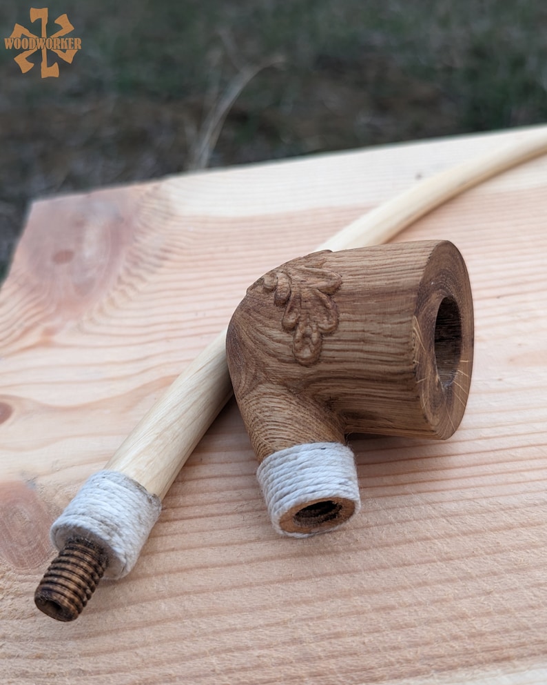 Pu&ograve; includere: Una pipa da fumo in legno con un motivo a foglia intagliato e una corda bianca avvolta attorno al gambo. La pipa &egrave; realizzata in legno marrone chiaro e ha una finitura naturale.