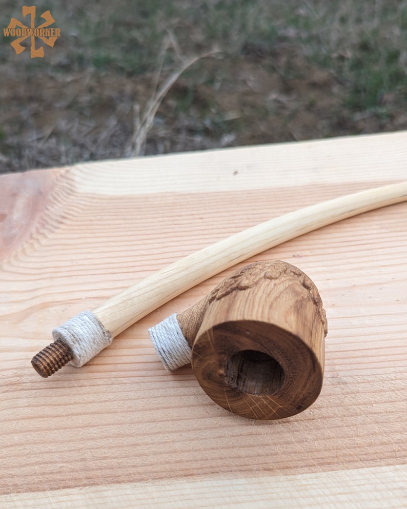 Pu&ograve; includere: Una pipa da fumo in legno con un lungo stelo curvo. La ciotola della pipa &egrave; intagliata con un disegno e ha una corda bianca avvolta attorno. Lo stelo ha anche una corda bianca avvolta attorno.